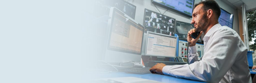 An IT professional with several monitors displaying information in front of him.